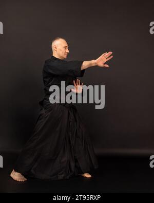 Portrait de maître de sensei aikido avec ceinture sensei noire en kimono taekwondo sur fond noir. Kimono traditionnel samouraï hakama. Mode de vie sain Banque D'Images