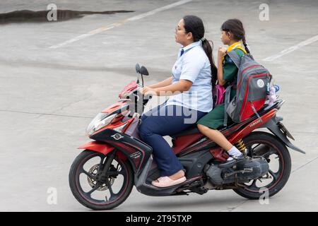 SAMUT PRAKAN, THAÏLANDE, NOVEMBRE 09 2023, Une femme conduit une moto avec une fille en uniforme scolaire Banque D'Images