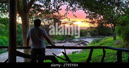 Maasai Mara, Kenya, 23-décembre-2020 - Un touriste profite d'un moment de calme tout en contemplant un coucher de soleil glorieux sur la réserve de gibier Maasai Mara Banque D'Images