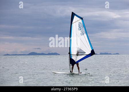 Planche à voile en mer, sports nautiques. Vue sur le windsurfer de l'homme et les îles dans la brume, paysage marin pittoresque Banque D'Images