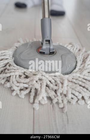 Enfant avec une vadrouille blanche moderne nettoyant le plancher en bois Banque D'Images