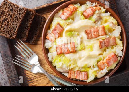 Poisson traditionnel norvégien Plukkfisk cuit avec purée de pommes de terre, garni de savoureux bacon en gros plan sur une assiette sur la table. Vue de dessus horizontale à partir d'un Banque D'Images