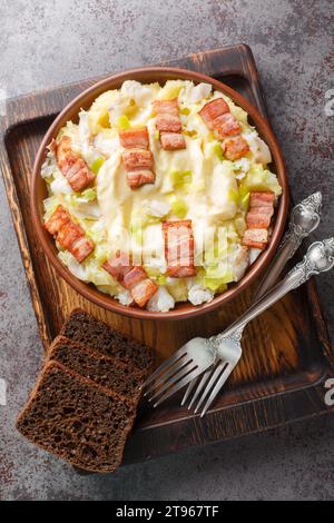 Scandinave plukfisk est fait avec de la morue légèrement salée sur de la purée de pommes de terre, garnie de savoureux bacon en gros plan sur une assiette sur la table. Haut vertical vi Banque D'Images