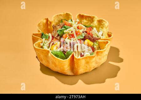 Salade de tacos dans un bol de tortilla avec du bœuf, du fromage, du maïs et de la laitue. Banque D'Images