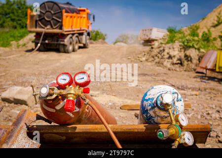 Équipements de soudage rouge et bleu, réservoirs d'oxygène et d'azote avec vannes et manomètres, bouteilles de gaz d'acétylène placées sur des pieux métalliques à la construction Banque D'Images