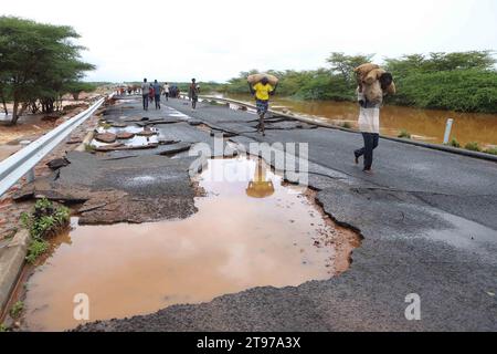 Nairobi. 22 novembre 2023. Les gens transportent des marchandises le long d’une route détruite après que les véhicules ont été empêchés de traverser la région à la suite de fortes pluies sur la route Thika-Garissa dans le nord du Kenya le 22 novembre 2023. Selon la Société de la Croix-Rouge kényane, au moins 71 personnes sont mortes, plus de 200 blessées et plus de 150 000 autres déplacées à travers le pays, les fortes pluies continuant de causer des ravages. Crédit : Joy Nabukewa/Xinhua/Alamy Live News Banque D'Images