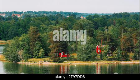 Vue panoramique sur de nombreux bois suédois rouge sauna en bois cabanes maisons sur la côte de l'île en été jour nuageux. Maisons en bois de vieille tradition suédoise. Gras Banque D'Images