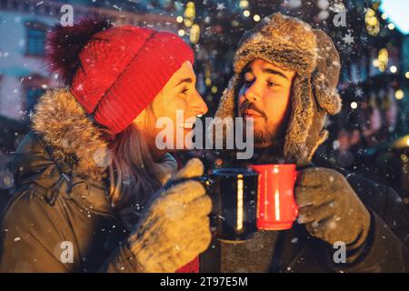 Couple griller avec du vin chaud sur un marché de Noël Banque D'Images