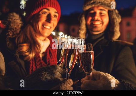 Couple grillage avec des verres à champagne dans la soirée d'hiver à un marché de noël Banque D'Images