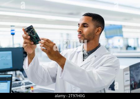 Électrotechnicien Comptenet vérifiant la carte mère dans l'usine d'électronique Banque D'Images