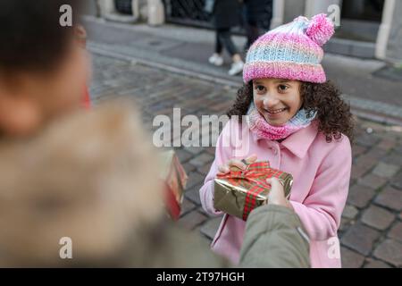 Frère donnant une boîte cadeau à la sœur souriante dans la rue Banque D'Images