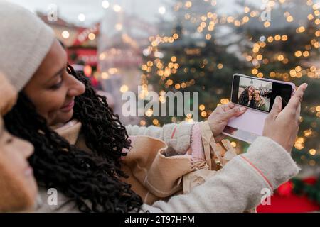 Mère prenant selfie avec son fils par téléphone intelligent au marché de Noël Banque D'Images