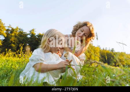 Mère et fille souriantes s'accroupant sur l'herbe Banque D'Images