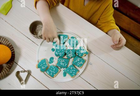 Garçon décorant des biscuits sur l'assiette à la table à manger Banque D'Images