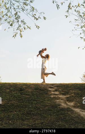 Mère joueuse tenant bébé garçon dans le parc Banque D'Images