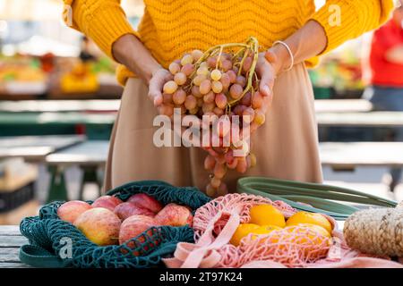 Femme tenant bouquet de raisins frais au marché fermier Banque D'Images