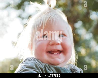 Bébé fille souriante avec les cheveux blonds dans le parc Banque D'Images