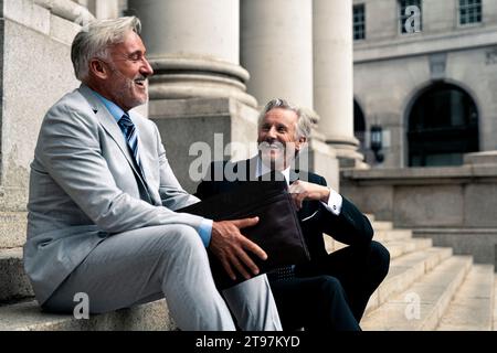 Heureux hommes d'affaires seniors assis ensemble sur des marches Banque D'Images