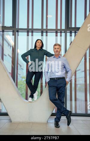 Homme d'affaires avec femme d'affaires debout sur la colonne architecturale Banque D'Images