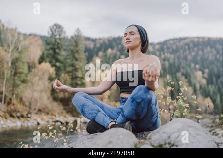 Femme assise sur le rocher et méditant dans la forêt Banque D'Images