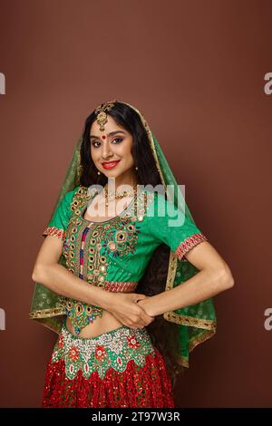 plan vertical de la belle femme indienne avec les cheveux longs et le voile vert souriant joyeusement à la caméra Banque D'Images