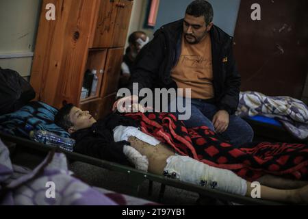 Khan Yunis, Territoires palestiniens. 23 novembre 2023. Des Palestiniens blessés reposent dans une salle de classe de l’école de Ras Al-Naqoura à Khan Yunis, dans le sud de la bande de Gaza, après avoir été transférés de l’hôpital indonésien dans le nord, au milieu des combats en cours entre Israël et le groupe militant palestinien Hamas. Une trêve temporaire convenue par Israël et le Hamas doit commencer vendredi à 7 h (0500 h GMT). Crédit : Mohammed Talatene/dpa/Alamy Live News Banque D'Images