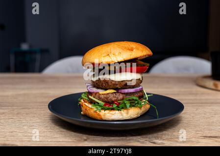 Hamburger double maison reposant sur une assiette sur la table de la salle à manger. Banque D'Images