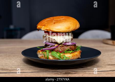 Hamburger double maison reposant sur une assiette sur la table de la salle à manger. Banque D'Images