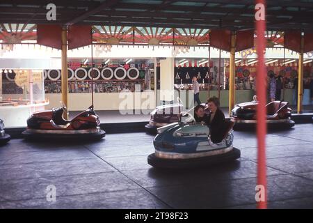 1968, historique, été et une mère et son fils s'amusant ensemble dans une voiture de dodgem à un parc d'expositions, Angleterre, Royaume-Uni. Également connus sous le nom de voitures tamponneuses, car ces petites voitures électriques avec des pare-chocs en caoutchouc tout autour sont conçus pour «cogner» dans les autres voitures de ce type et sont un manège d'amusement traditionnel lors d'une fête foraine britannique. Banque D'Images