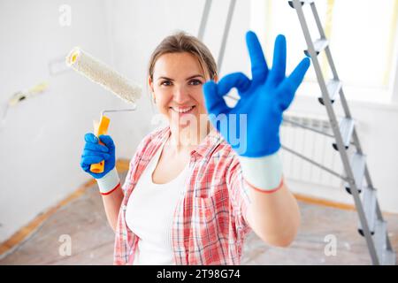 Jeune femme souriante avec brosse à rouleaux montrant le geste ok, espace de copie Banque D'Images