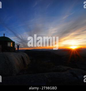 Petit garçon levant les mains devant un sablier au coucher du soleil sur le sommet de la montagne Styggemann en Norvège nuages et ciel étonnants Banque D'Images