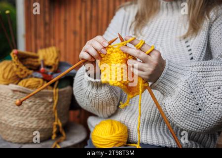 Tricoter avec de la laine. Femme en pull en laine tricote des vêtements chauds de fil jaune Banque D'Images