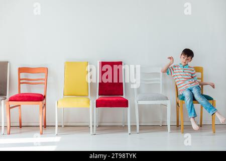 garçon et de nombreuses chaises différentes à l'intérieur d'une pièce blanche Banque D'Images