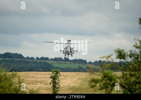 Gros plan d'un hélicoptère d'attaque Boeing Apache de l'armée britannique AH64E AH-64E planant à basse altitude au-dessus de la campagne estivale Banque D'Images