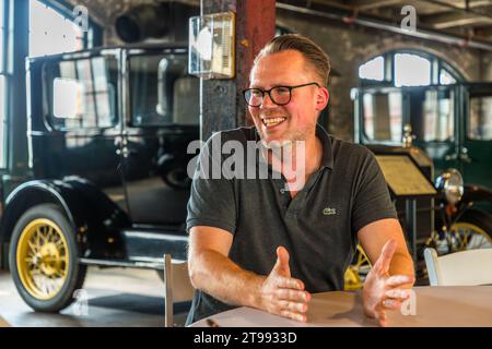 Un entrepreneur allemand rit lors de sa conversation avec la journaliste Angela Berg au Ford Piquette Plant à Detroit, Michigan, États-Unis. Deux véhicules historiques Ford Model T se dressent en arrière-plan. Construit en 1904, le Ford Piquette Plant est considéré comme le plus ancien bâtiment survivant initialement construit à des fins de production automobile et encore ouvert au public. Henry Ford y a développé la Ford Model T en 1907, la production en série commençant en 1908. Banque D'Images