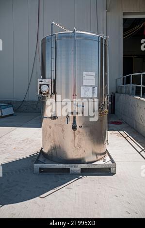 Un réservoir en acier inoxydable, à l'extérieur sur une palette métallique dans un entrepôt de réfrigération industrielle au CO2 (stockage à froid) en construction. Banque D'Images