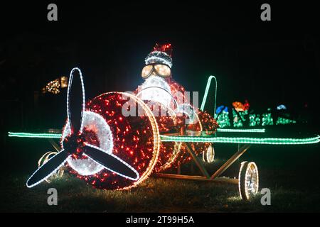 Décor de rue de Noël fait à partir de guirlandes dans l'obscurité .Père Noël sur une installation lumineuse d'hélicoptère. Banque D'Images