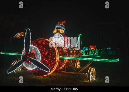 Père Noël sur une installation lumineuse d'hélicoptère. Décor de rue de Noël en guirlandes. Figurines de Noël éclatantes Banque D'Images