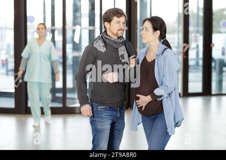homme aidant une femme lourdement enceinte dans le hall de l'hôpital Banque D'Images