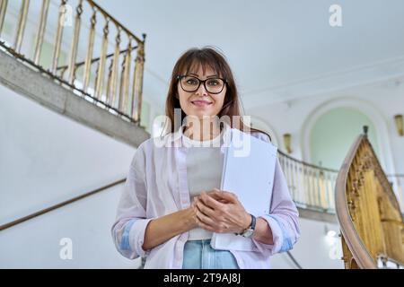 Portrait d'une enseignante d'âge moyen posant à l'intérieur d'un bâtiment éducatif Banque D'Images