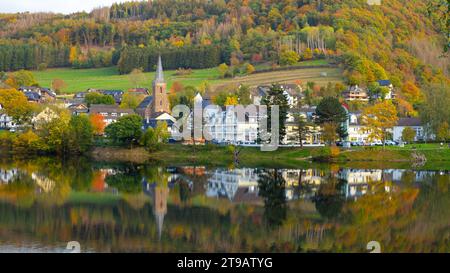 Beau village allemand avec forêt de feuillage coloré en arrière-plan et reflet dans le lac Rursee, Einruhr, Simmerath Banque D'Images