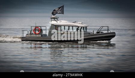 Les pirates modernes sur un bateau à moteur dans une baie sous un drapeau pirate Banque D'Images