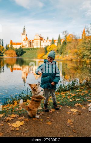 Un garçon avec un chien corgi près du lac dans le château de Pruhonice Banque D'Images