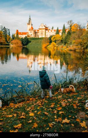 Un garçon avec un chien corgi près du lac dans le château de Pruhonice Banque D'Images