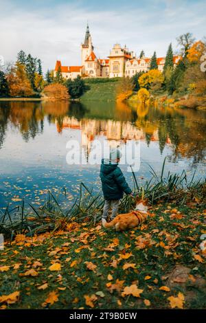 Un garçon avec un chien corgi près du lac dans le château de Pruhonice Banque D'Images