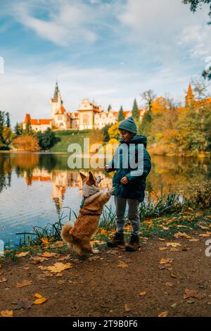 Un garçon avec un chien corgi près du lac dans le château de Pruhonice Banque D'Images