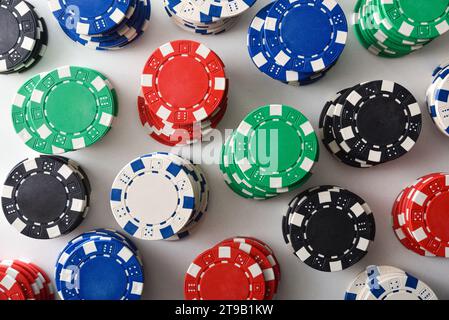 Fond avec motif de piles de jetons de casino colorés sur une table blanche. Vue de dessus. Banque D'Images