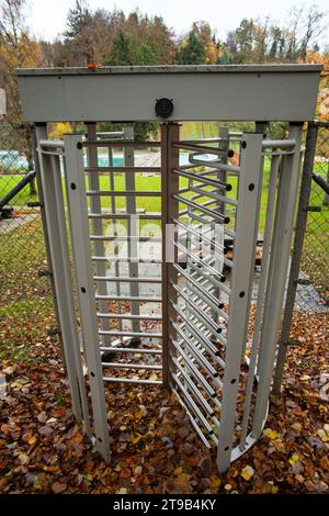 Des tourniquets métalliques tournants sécurisent l'accès à un parc public dans une forêt. Couleurs d'automne, jour nuageux, pas de gens. Banque D'Images