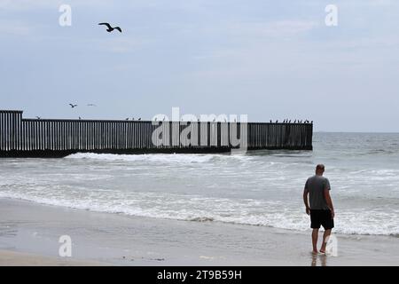 San Diego, CA, États-Unis - 30 juillet 2023 : touriste près du mur frontalier des États-Unis Mexique dans Border Field State Park Beach. Banque D'Images