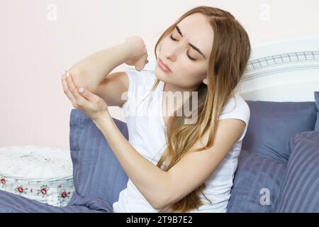 Soins de santé et concept médical. Femme se grattant le coude. Femme se grattant le bras et le coude à cause de la peau sèche à la maison. Banque D'Images